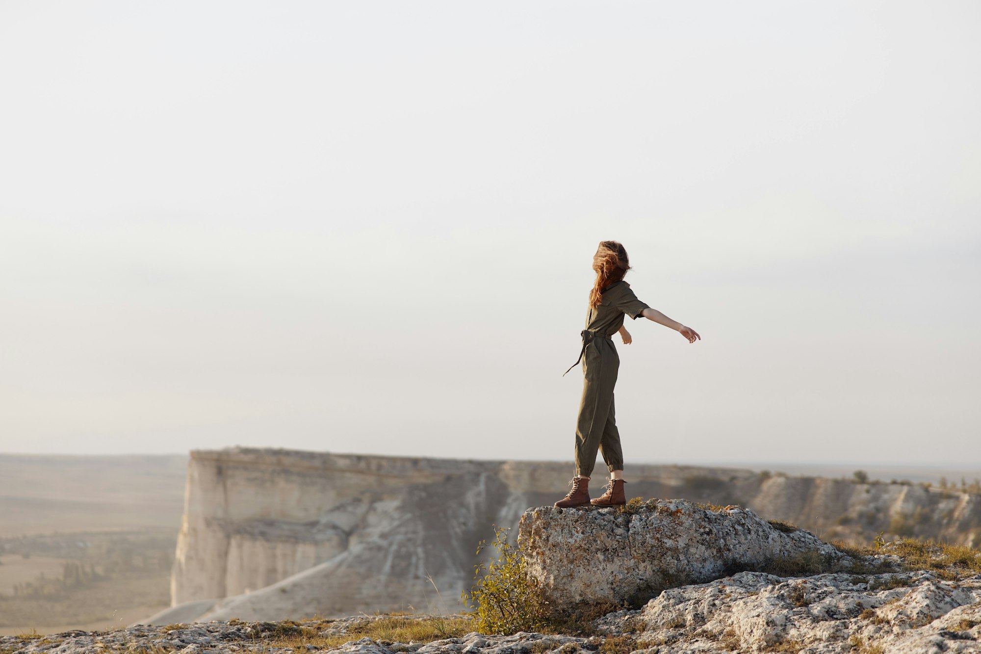 Woman standing on top of a majestic rock with arms outstretched in the air, feeling the freedom of