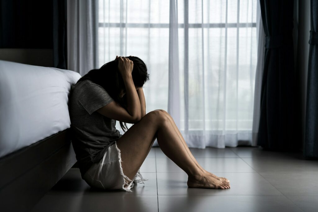 Lonely young woman feeling depressed and stressed sitting in the dark bedroom, Negative emotion